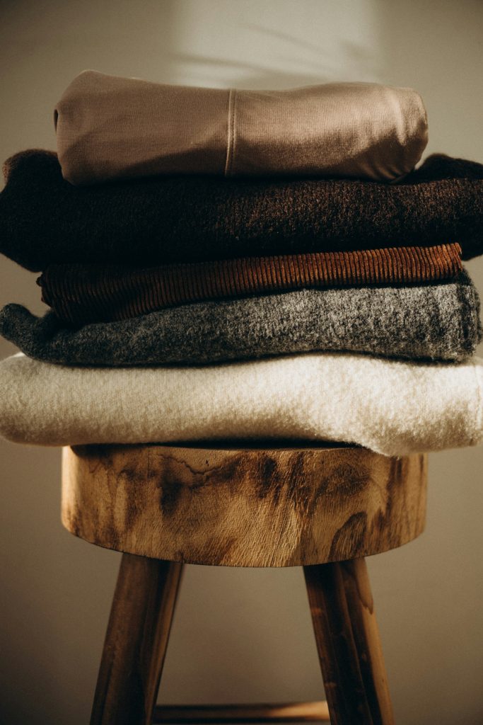 Stack of folded knitwear on a wooden stool